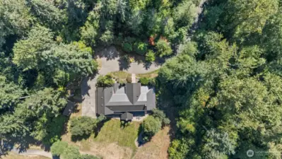 Smart-home design with expansive floor-to-ceiling windows, integrated sprinkler system, whole-house vacuum, and standby generator for uninterrupted comfort. High-end metal roof adds both architectural distinction and long-term durability. Serene, tree-lined drive winds through a natural canopy, offering a peaceful journey to the home’s front entrance.