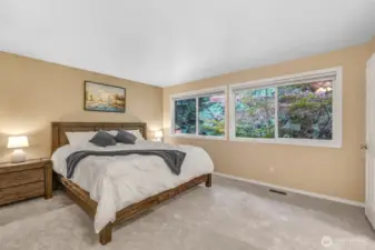 The primary bedroom is spacious and serene, with oversized windows that frame tranquil views of the surrounding evergreens. This restful retreat offers the perfect escape at the end of the day.