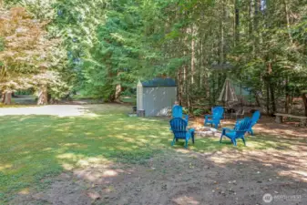 From here you can see both the firepit and the wide-open yard beyond. This portion of the property is well suited for outdoor recreation and gatherings.