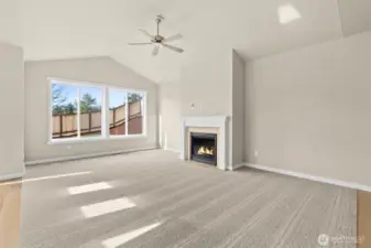Light and bright open living room with vaulted ceilings and ceiling fan.