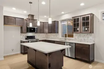 Kitchen features Cocoa-stained Maple Cabinets and Quartz countertops. Whirlpool stainless steel gas double oven is standard.
