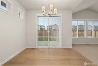 Dining area features hardwood flooring and a glass slider that opens to backyard and patio area.