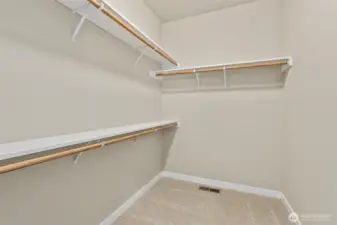Primary closet is walk-in with extra storage shelves above the hanging rods.