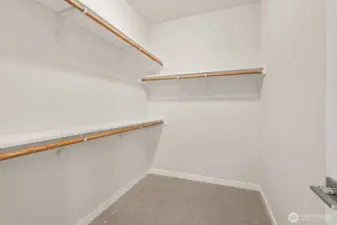 Primary closet is walk-in with extra storage shelves above the hanging rods.