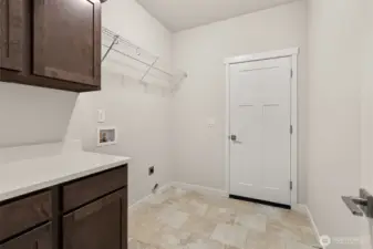 Separate laundry room with a counter, storage cabinets and a storage shelf above appliances.
