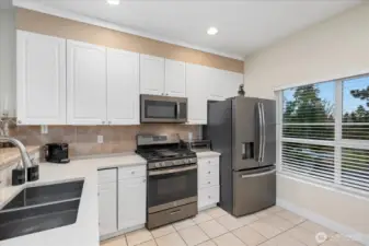 Bright kitchen with quartz counters, backsplash tiles, and black stainless steel appliances.