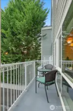 Cozy balcony with treetop outlook and seating.