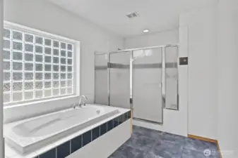 The soaking tub and shower with double shower heads are surrounded by tile.
