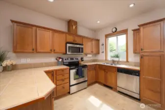 At the top of the stairs just to the left is this spacious kitchen as well as a 1/2 bath and outside deck.  Lots of light year round. So much storage and SS appliances all stay!