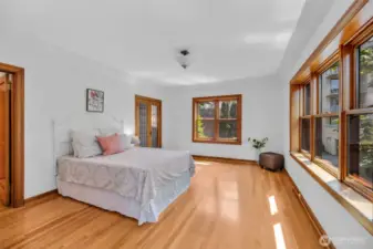Walls of windows & hardwood floors glow with natural light.