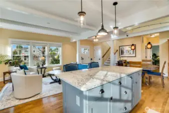 Looking back toward the living room and entry, you can see just how open and bright this floor plan feels. Look at the sunshine streaming through! The island offers additional storage for all your kitchen essentials.