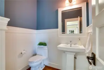 Just off the living area, this charming half bath pairs classic wainscoting and beadboard accents with a framed mirror and pedestal sink. Added architectural details create a polished, welcoming space for all.
