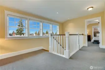 A wall of windows brightens the landing with natural light. Upgraded window coverings add both style and privacy.