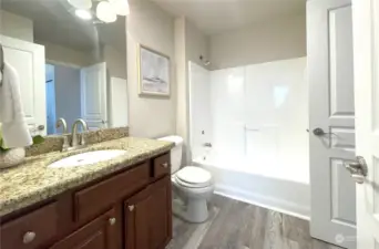 Step into this contemporary bathroom featuring a sleek tub-shower combo and striking granite counters. The modern design seamlessly blends style and functionality, creating a refreshing and inviting space to unwind.