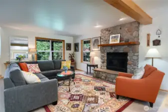 The striking river rock-framed gas fireplace creates a warm and inviting focal point, perfect for cozy evenings and gathering with family and friends in the front living room.