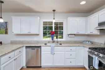 This kitchen shines with clean white cabinetry and countertops, featuring modern stainless steel appliances and a gas cooking stove—perfect for both everyday meals and gourmet cooking.