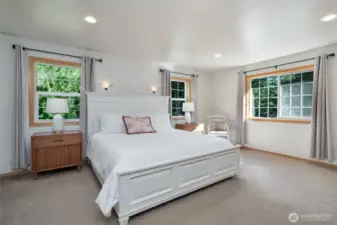 The primary bedroom features corner windows that flood the space with natural light, creating a warm and airy retreat perfect for relaxation.