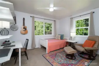 This second-story bedroom features corner windows that welcome abundant morning sunlight, creating a bright and cheerful space to start the day.