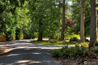 A raised gravel driveway gently ascends to meet the spacious circular drive, creating a clean, elevated approach to the home. This thoughtful design not only enhances curb appeal but also ensures smooth navigation—whether you're arriving in a car, RV, or trailer.