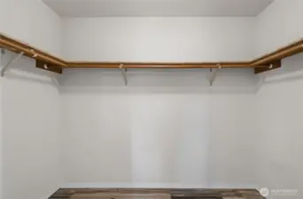 Generous walk-in closet features custom shelving and multiple hanging zones for organized storage.