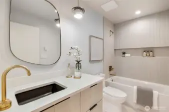 Chic Bath Design: The tub shower, complete with a tiled surround and a convenient niche, combines style with practicality.
