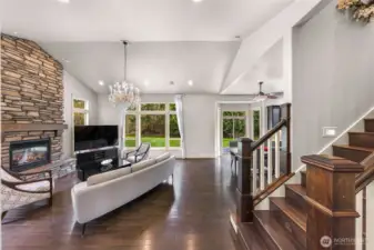 Bright living room with stone fireplace, wood staircase, and open layout