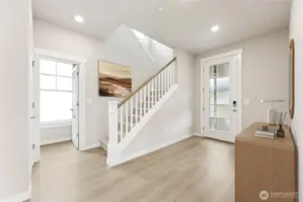 Large entry foyer with full glass front door and open railing.