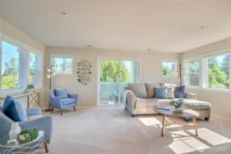 Living room with windows on 3 sides, fireplace and balcony to enjoy relaxing with friends.