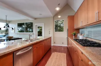 Open floorplan filled with natural light, the kitchen at entry boasts large island of custom cabinets, seating area and dining room (door leads to large outdoor deck).