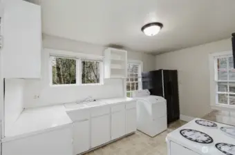 Kitchen with gas dryer by refrigerator.