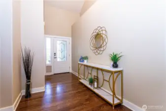 Step inside to a bright and open entryway with high ceilings, fresh paint, and rich hardwood floors. This foyer sets the tone for the entire home—spacious, elegant, and thoughtfully designed. Natural light pours through the glass door, highlighting the clean lines and warm color palette. It’s the kind of entrance that feels both inviting and impressive.