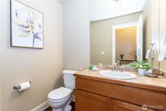 Conveniently located on the main level, the powder room features a tile countertop vanity, framed mirror, and updated fixtures. Soft wall tones and accent décor make it both functional and welcoming—perfect for guests and family alike.