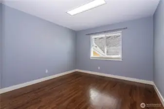 A large and open bedroom with hardwood floors and soft gray-blue walls. Ready to adapt as a home gym, hobby area, or additional office. The room’s simplicity and light make it easy to personalize.