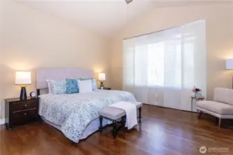 Beautiful and tranquil, this bedroom showcases vaulted ceilings, oversized windows, and refined finishes. Natural light fills the space, highlighting the elegant hardwood floors and soft palette that invites rest and rejuvenation.