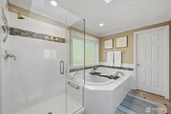 French doors lead you into updated primary bath offering tiled walk-in shower, heated tile flooring, soaking tub, double sink vanity with updated lighting, water closet, and large walk-in closet!