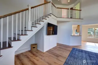 The great room with vaulted ceilings. Looking into the formal dining room. The hallway goes to the primary suite, down stairs half bath, utility room and garage. Lots of sunlight with this southern exposure.