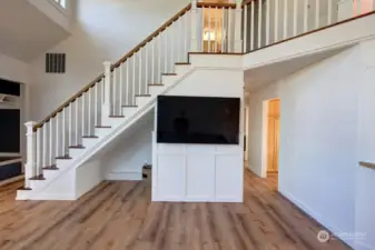 The great room with vaulted ceilings. Looking towards the stairway to the 2nd floor. The hallway goes to the primary suite, down stairs half bath, utility room and garage. Lots of sunlight with this southern exposure.