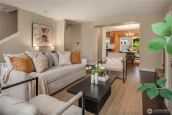 Looking across the main living room towards the dining room and kitchen. The stairs on the left lead up to two bedrooms and a den while the middle stairwell goes down to a third bedroom and 2 car garage.