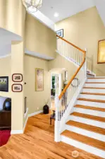 Entry interior. Dramatic, soaring ceiling with Traditional-style polished-brass-beveled-glass entry chandelier. Beautiful oak-hardwood floor. Elegant, atypical staircase with Traditional balustrade, oak-hardwood treads, formal painted risers. Hallway with archway opening and barrel-ceiling passageway to Family room. Entry coat closet with paneled door. Oak-hardwood floor extends into dining room, family room and hallway to Primary ensuite.