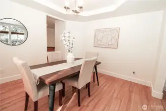 Elegant dining room with coffered ceiling detail, chandelier lighting, and seamless flow to the kitchen, ideal for both everyday meals and special occasions.