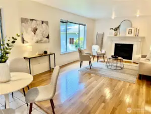 Bright and open family room features a beautiful fireplace, hardwood floors, and large window that floods the space with natural light.