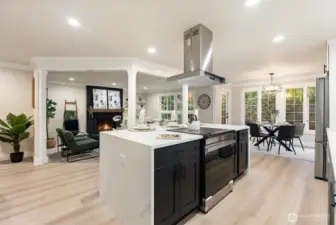 Chef’s kitchen anchored by large center island with waterfall-style quartz and statement range hood.