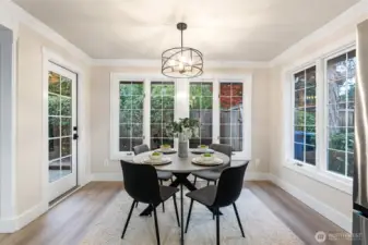 Breakfast nook framed by French doors and bay windows overlooking the backyard.
