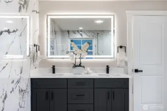 Double vanity with illuminated mirror and custom cabinetry.