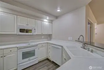Well adorned kitchen features newer appliances and lots of cupboards.