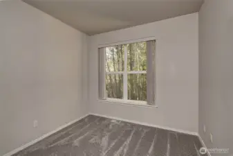 Generously sized guest bedroom with tranquil wooded views.