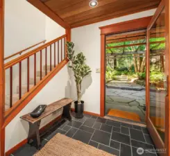 Welcoming entry with slate floor, warm wood ceiling and stairs to the upper levels. It's a happy place to call home.