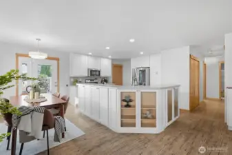 The beautifully remodeled kitchen is the heart of the home, featuring sleek corian countertops, crisp white cabinetry with custom storage solutions, stainless steel appliances, and display cabinets that blend style with function.
