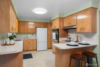 Timeless kitchen layout with generous counter space and abundant wood cabinetry for storage. A breakfast bar with seating creates a convenient spot for casual meals or morning coffee.