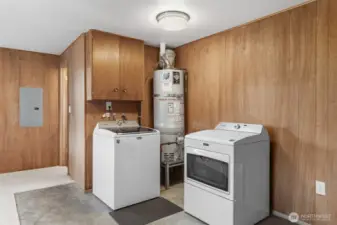 Dedicated laundry area with washer and dryer, plus nearby utility access for easy household tasks. Wood-paneled walls and built-in cabinetry provide additional storage and functionality.